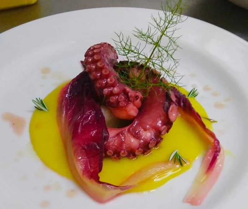 Tentacolo di polpo arricciato su crema gialla con radicchio rosso e finocchietto in piatto bianco, Al 76 da Michele